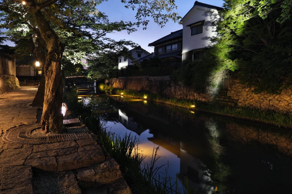 夜の八幡堀の風景。土蔵の白い壁のみをスプレッド型の集光照明で照らしている。